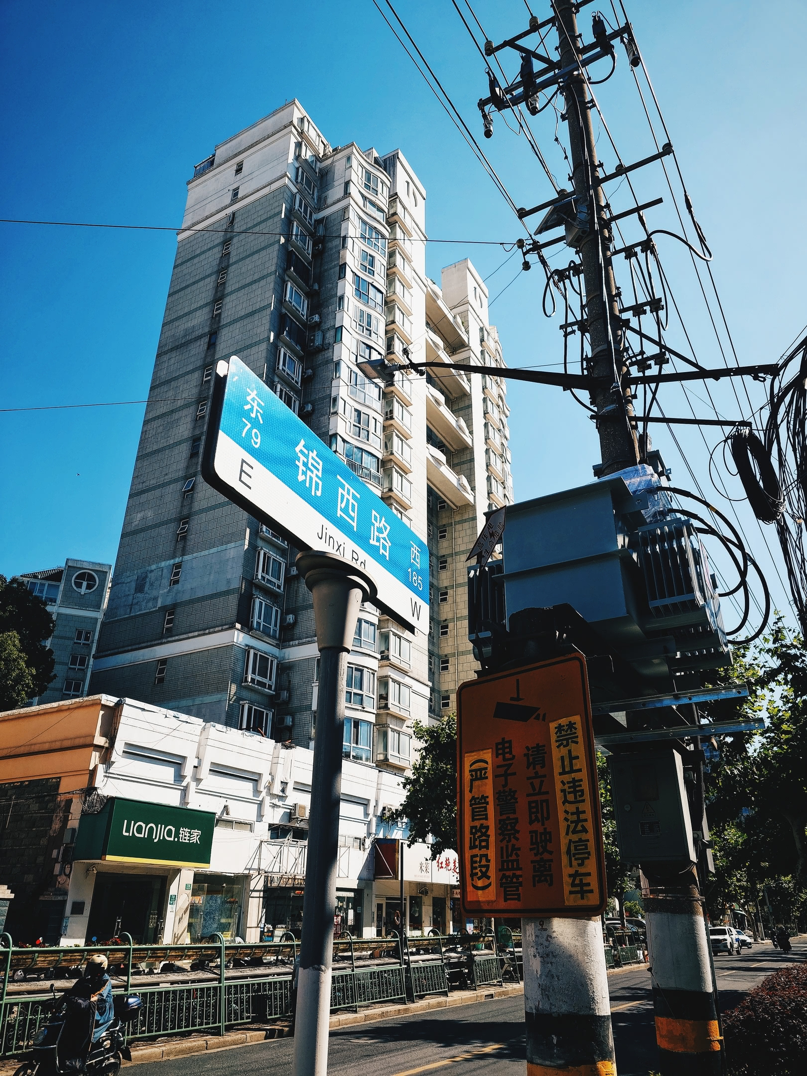 Intersection street sign with electrical power infrastructure and apartment building in background.