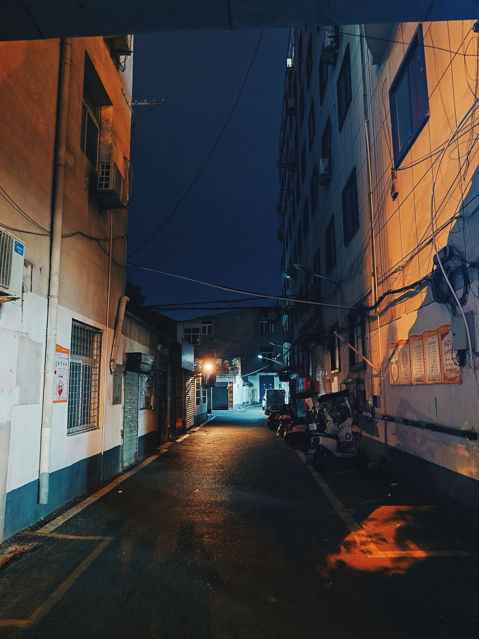 Residential alleyway with some garages at night.