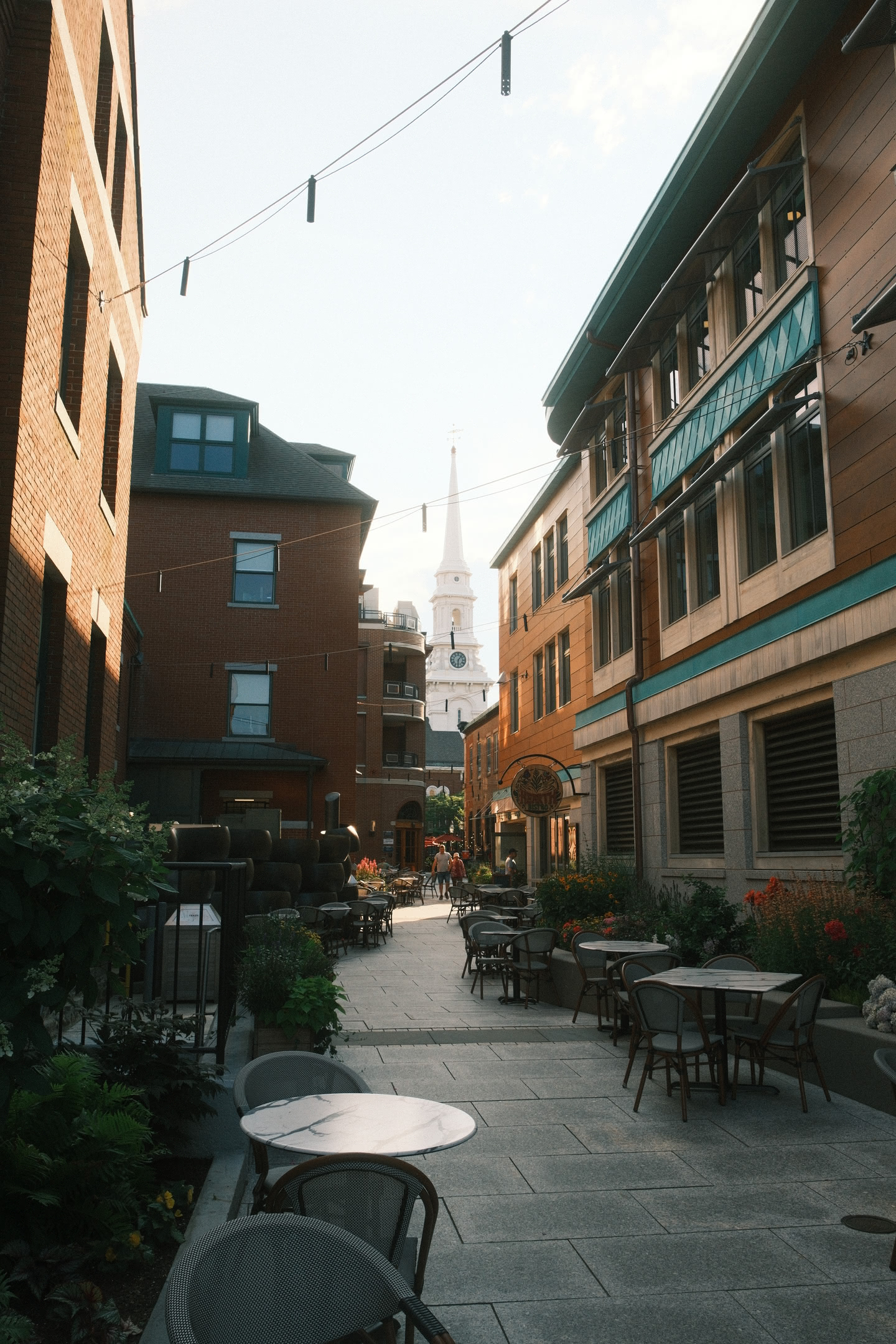 Empty alleyway with tables and chairs for brick-faced cafes and restaurants.